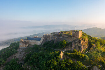 Fototapeta na wymiar Aerial view abour castle of Sirok with misty matra mountains at the background. Spring sunrise landscape.