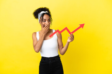 Young african american woman isolated on yellow background holding a catching a rising arrow with surprised expression