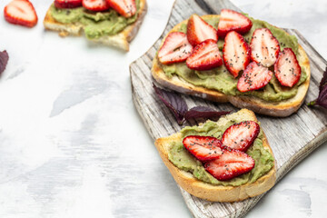 Delicious toast with avocado, strawberries, and chia seeds. Healthy summer snack. Delicious breakfast or snack, Clean eating, dieting, vegan food concept. top view