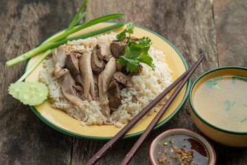 Sliced Hainan-style chicken and liver with marinated rice on wooden table.