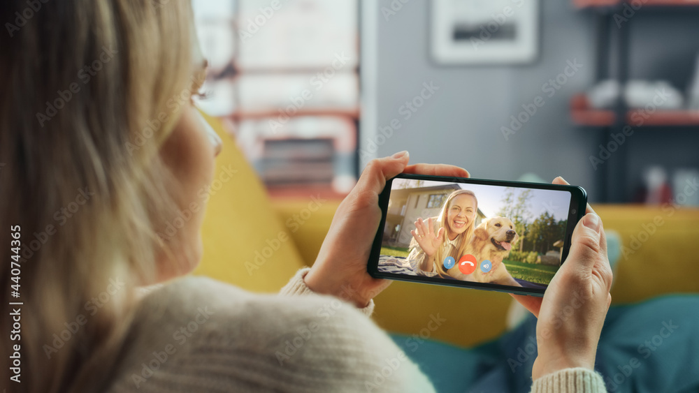 Poster close up of a female chatting in a video call with her beautiful friend playing with a dog on smartp