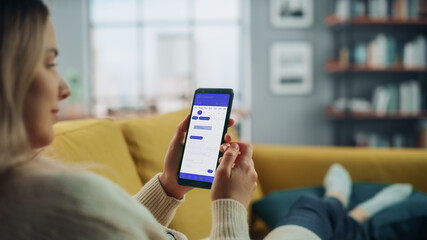 Beautiful Authentic Female Using a Smartphone with Calendar Application at Home Living Room while Lying on a Couch Sofa. She's Making Plans and Checking Event Schedule for a Day.