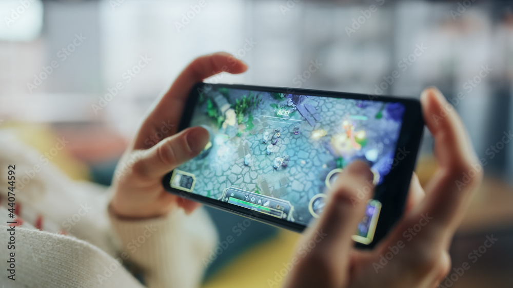 Aufkleber close up on hands playing an rpg strategy video game on a horizontally held smartphone at home livin