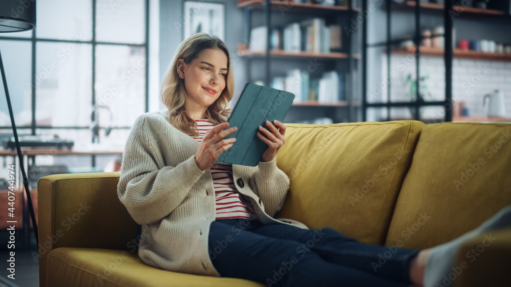 Aufkleber beautiful caucasian female using tablet computer in stylish living room while resting on a cozy couc
