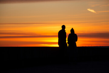 Fototapeta na wymiar People figures on the sunset background on the beach