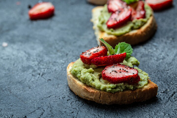Toast with mashed avocado, strawberries and chia seeds, Avocado with strawberries. Keto diet toast. Vegan healthy food concept. Top view