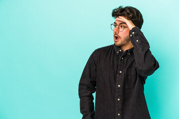 Young caucasian man isolated on blue background looking far away keeping hand on forehead.