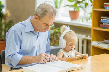 Little girl uses the application on the phone, and an elderly man reads a book in the library