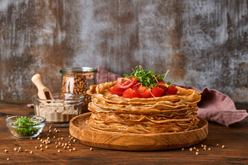 Stack of gluten free buckwheat flour crepes pancakes with cherry tomatoes and arugula microgreens...