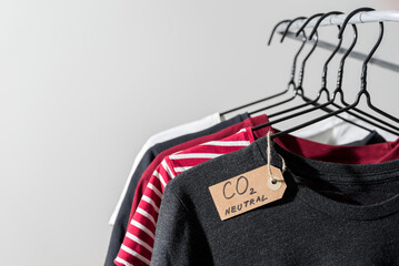 Clothes on hanger in rail with carbon emission paper recycled label