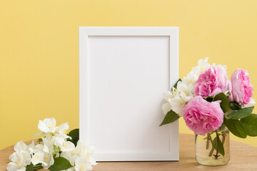 Empty white frame mock up with flowers on yellow background. Temlate for your text or picture