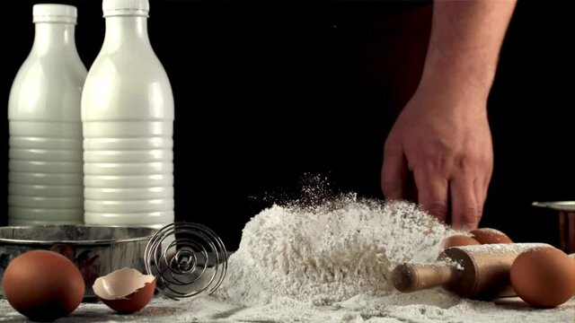 Super slow motion raw egg falls in a pile of flour on the table. On a black background. Filmed on a high-speed camera at 1000 fps.