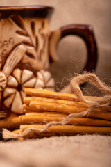 Breadsticks with salt tied with string and an earthenware mug for tea. Close-up Selective focus.