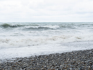 Storm waves on a stone beach in cloudy weather