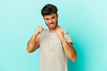 Young caucasian man isolated on blue background upset screaming with tense hands.