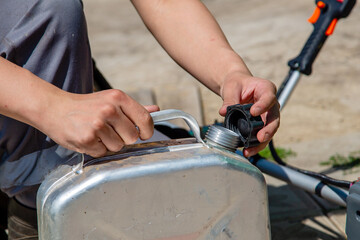 Obraz premium A man opens a canister of fuel. Lid in hand close-up