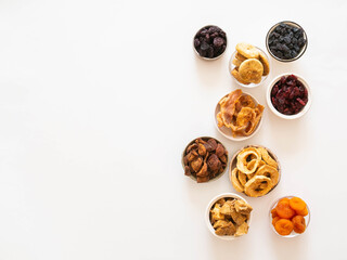 Flat lay various dried fruits and berries in bowls on white background Vegan healthy natural snacks.