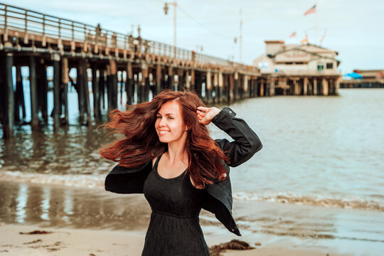 Beautiful young woman with long hair happily twirling on the beach in Santa Barbara, California, USA