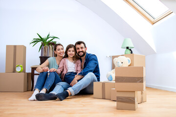 Portrait of happy smiling caucasian family being in their new house and cardboard boxes around them.
