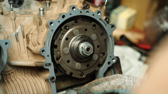a man in work gloves installs a gasket between the engine and the gearbox
