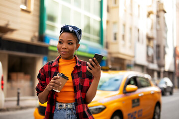 Young african woman using the phone while drinking coffee. Beautiful woman talking to the phone