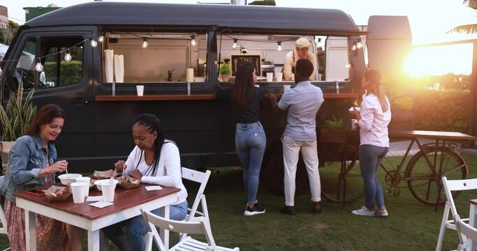 Multiracial people ordering gourmet food in front of food truck outdoor - Multigeneratiol friends having fun eating dinner outside at summer time