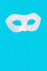 Sadness and loneliness expressed by a theatrical mask with tears on a blue background. Creative minimal expression of sadness, rejection, broken heart.