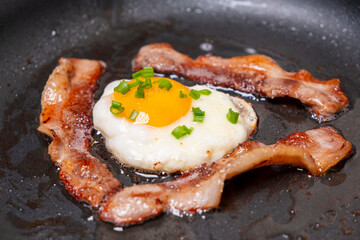 fried bacon with eggs in a pan. tasty breakfast
