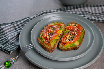 Plate with delicious sandwiches, bruschetta, or toast with avocado and trout or salmon on a concrete table. Delicious breakfast concept

P