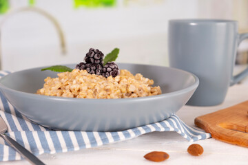 Breakfast in the kitchen, oatmeal with nuts and berries. Healthy food concept