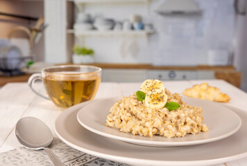 Oatmeal with bananas and fruits and tea, healthy breakfast in the kitchen