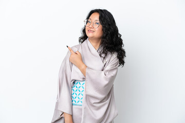 Young asian woman wearing kimono isolated on white background pointing to the side to present a product