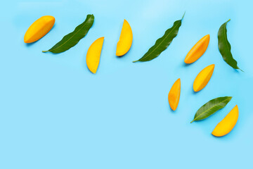Fototapeta premium Tropical fruit, Mango slices with leaves on blue background.