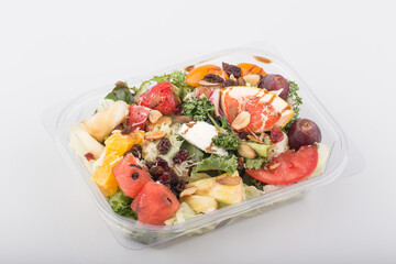 Fruit and vegetable salad in a package on white table.
