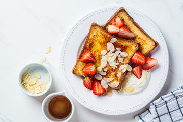 French toast with strawberries, yogurt and maple syrup on a white plate. Breakfast concept.