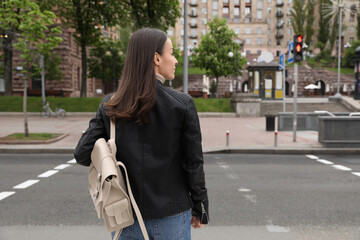 Young woman waiting at traffic lights to cross street, back view