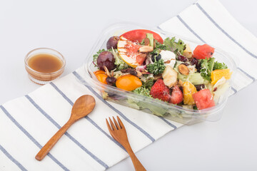 Fruit and vegetable salad in a package on white table.