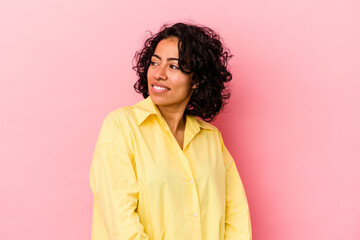 Fototapeta premium Young curly latin woman isolated on pink background looks aside smiling, cheerful and pleasant.