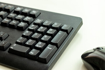 白い机に置かれた黒のキーボードと黒のマウス