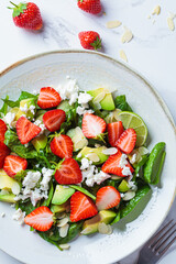 Close-up of strawberry salad with spinach, feta cheese, avocado and almonds.