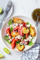 Italian salad with tomatoes, feta cheese and grilled ciabatta, marble background.