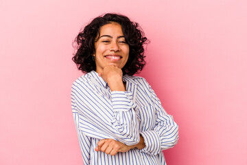 Young curly latin woman isolated on pink background smiling happy and confident, touching chin with...
