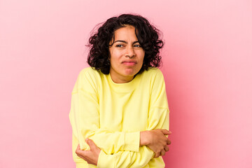 Young curly latin woman isolated on pink background shrugs shoulders and open eyes confused.