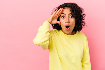 Young curly latin woman isolated on pink background looking far away keeping hand on forehead.