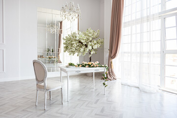 luxurious bright spacious guest room with beautiful chic furniture a huge floor-to-ceiling window in a royal style is decorated with green plants, white walls with stucco and a fireplace