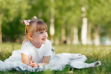 Happy little girl plays on the grass in the park in the summer