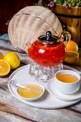 red berry tea in a transparent glass kettle with a mug of tea
