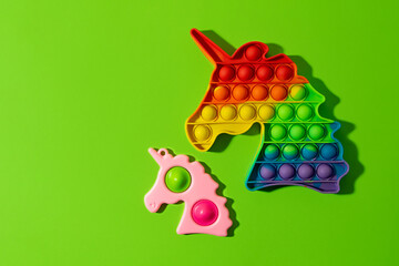Two anti stress fidgets - pop it and simple dimple on the green background.New sensory anti stress toy for children and adult.Trendy rainbow coloring.