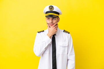 Airplane caucasian pilot isolated on yellow background having doubts and with confuse face expression