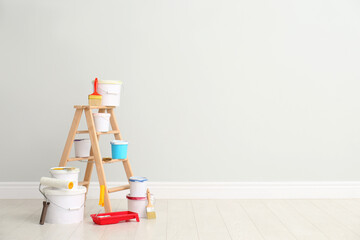 Decorator's kit of tools and paints near light wall indoors. Space for text